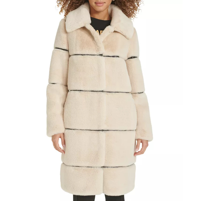A knee-length, beige faux-fur coat with horizontal black faux-leather trim details, featuring a wide collar and long sleeves.