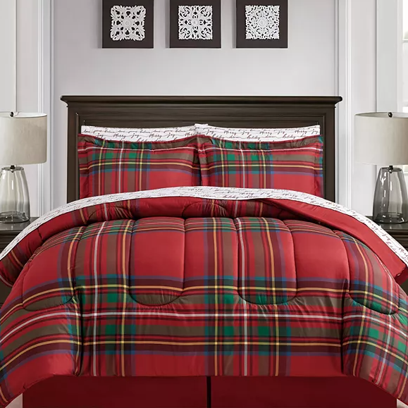 A red and green plaid comforter set with two matching pillow shams on a bed, complemented by decorative framed art and a table lamp.