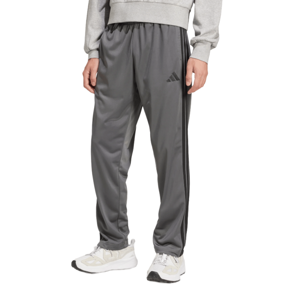Gray athletic track pants with a three-stripe design and brand logo, paired with white sneakers and a gray sweatshirt.