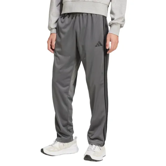 Gray athletic track pants with a three-stripe design and brand logo, paired with white sneakers and a gray sweatshirt.