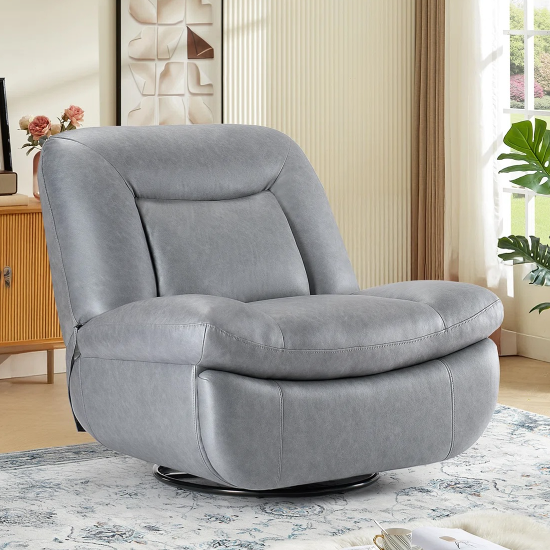 A gray leather swivel chair with a rounded, cushioned design is set in a cozy living room, featuring a patterned rug, a wooden cabinet, wall art, and a window with curtains.
