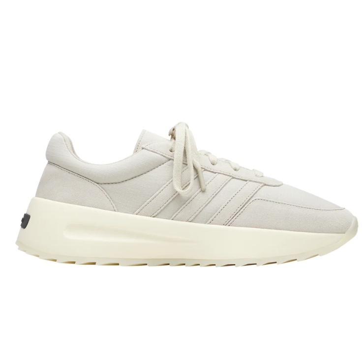 Beige sneaker with side stripes, lace-up closure, and a thick off-white sole.