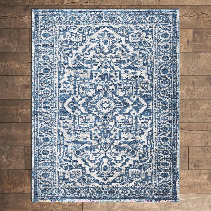 A blue and white area rug with a traditional, intricate pattern lies on a hardwood floor.