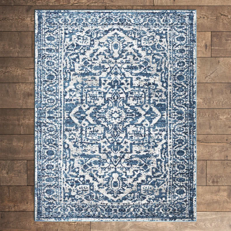 A blue and white area rug with a traditional, intricate pattern lies on a hardwood floor.