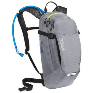 A gray CamelBak M.U.L.E. hydration backpack with a blue drinking tube and multiple compartments, designed for outdoor activities.