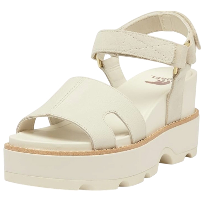 Cream-colored Sorel platform sandals with an adjustable ankle strap and a crisscross front strap, featuring a thick, grooved sole for added traction.