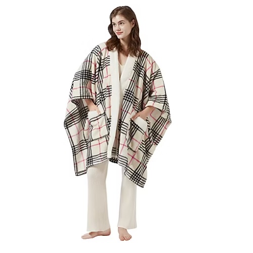 A person wearing a plaid-patterned cape with large black stripes and pink accents, paired with a cream outfit.