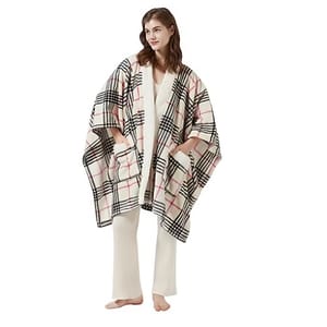 A person wearing a plaid-patterned cape with large black stripes and pink accents, paired with a cream outfit.