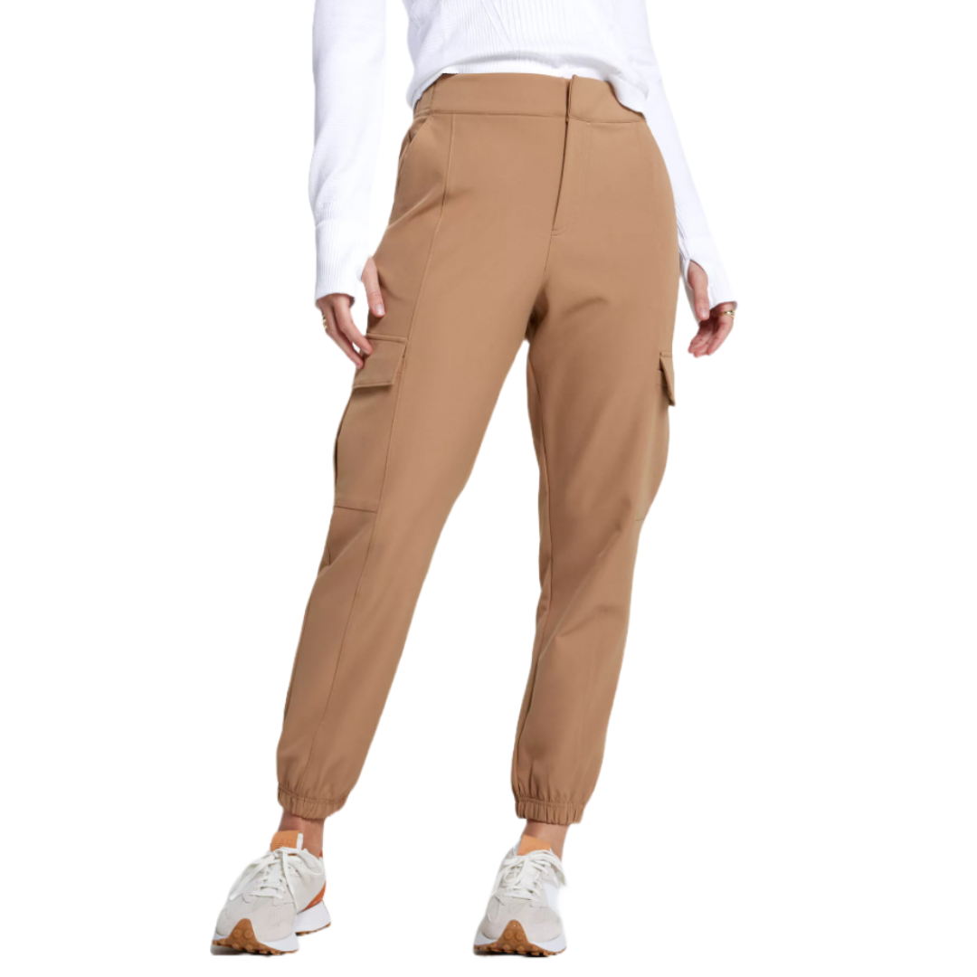 Women's tan crepe joggers with a relaxed fit, featuring cargo pockets, elastic cuffs, and a high waistband, paired with white sneakers and a white ribbed long-sleeve top.