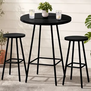 A black round bar table with two matching stools, designed for outdoor use. The setup is decorated with potted plants and drinks, set on a concrete surface against a light paneled background.