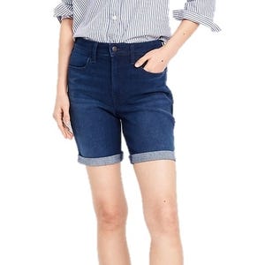 Dark blue denim shorts with rolled cuffs, featuring a button and zipper closure, front and back pockets, and paired with a striped shirt.
