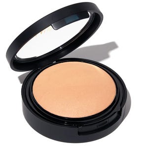 Laura Geller Full Coverage Foundation is in a compact with a black lid, featuring a pressed powder with a smooth, matte finish suitable for creating an even skin tone.