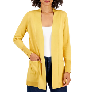 A woman wearing a yellow cardigan with ribbed cuffs and button accents, paired with a white top and dark jeans.