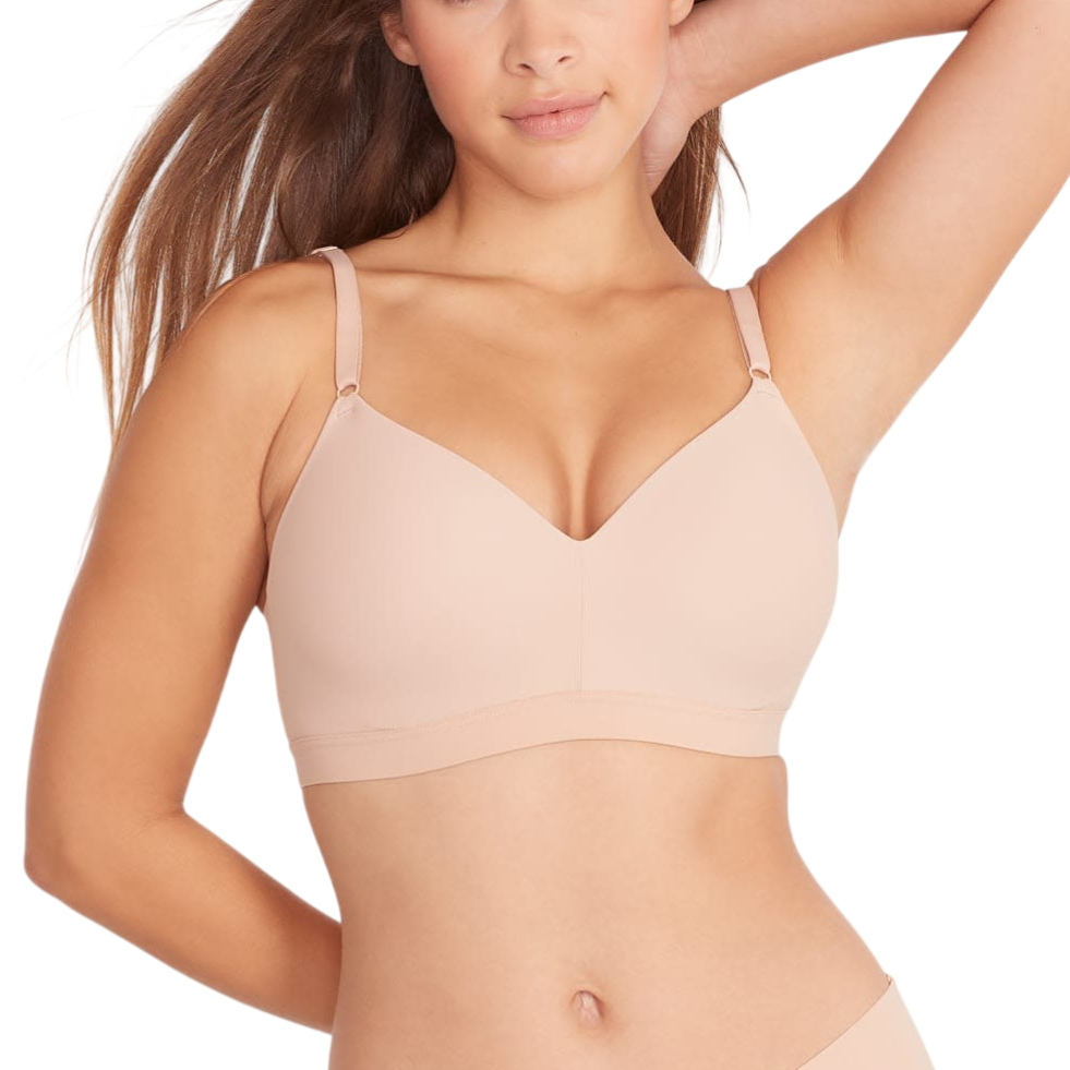 A woman models a nude-colored wireless bra with thin adjustable straps, paired with matching seamless underwear.