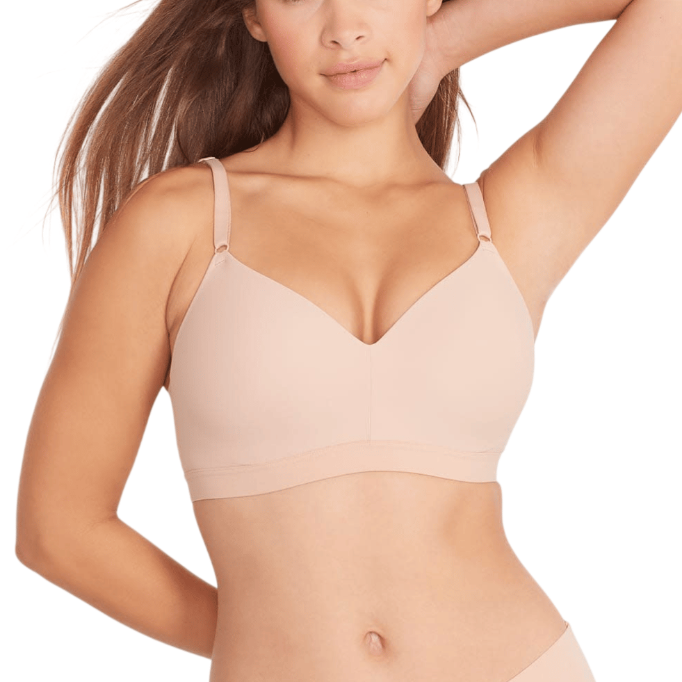 A woman models a nude-colored wireless bra with thin adjustable straps, paired with matching seamless underwear.