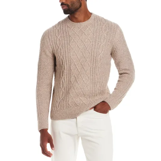 A beige cable-knit sweater paired with white pants, featuring a textured pattern and a round neckline.