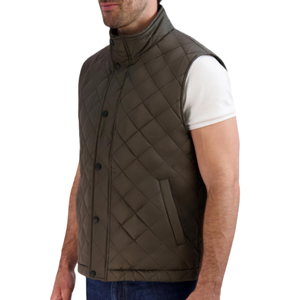 A Cole Haan diamond quilted vest in olive features a high collar, button-down front, and two side pockets. The vest is sleeveless and worn over a white short-sleeve shirt.