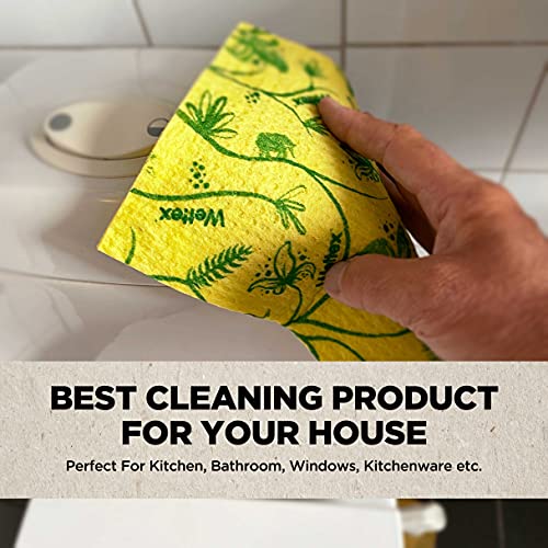 A hand is wiping a surface with a yellow Swedish dishcloth adorned with green botanical patterns.