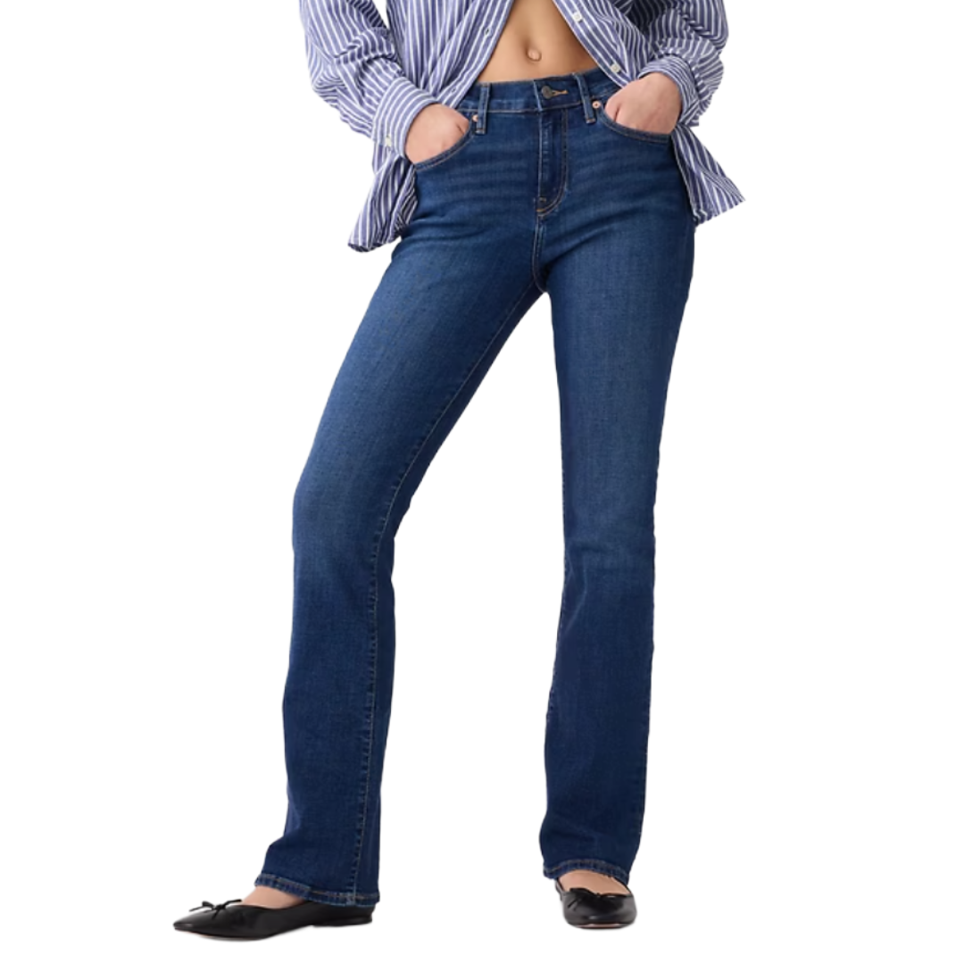 A person is wearing bootcut jeans paired with a blue and white striped shirt and black ballet flats.