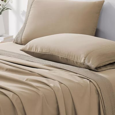 A beige pillow and matching bedsheet set featuring a subtle stripe detail, arranged neatly on a bed.