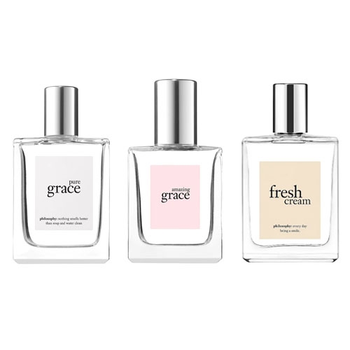 Three Philosophy fragrances in clear, rectangular glass bottles, each with a silver cap and labeled respectively: \“pure grace,\“ \“amazing grace,\“ and \“fresh cream.\“