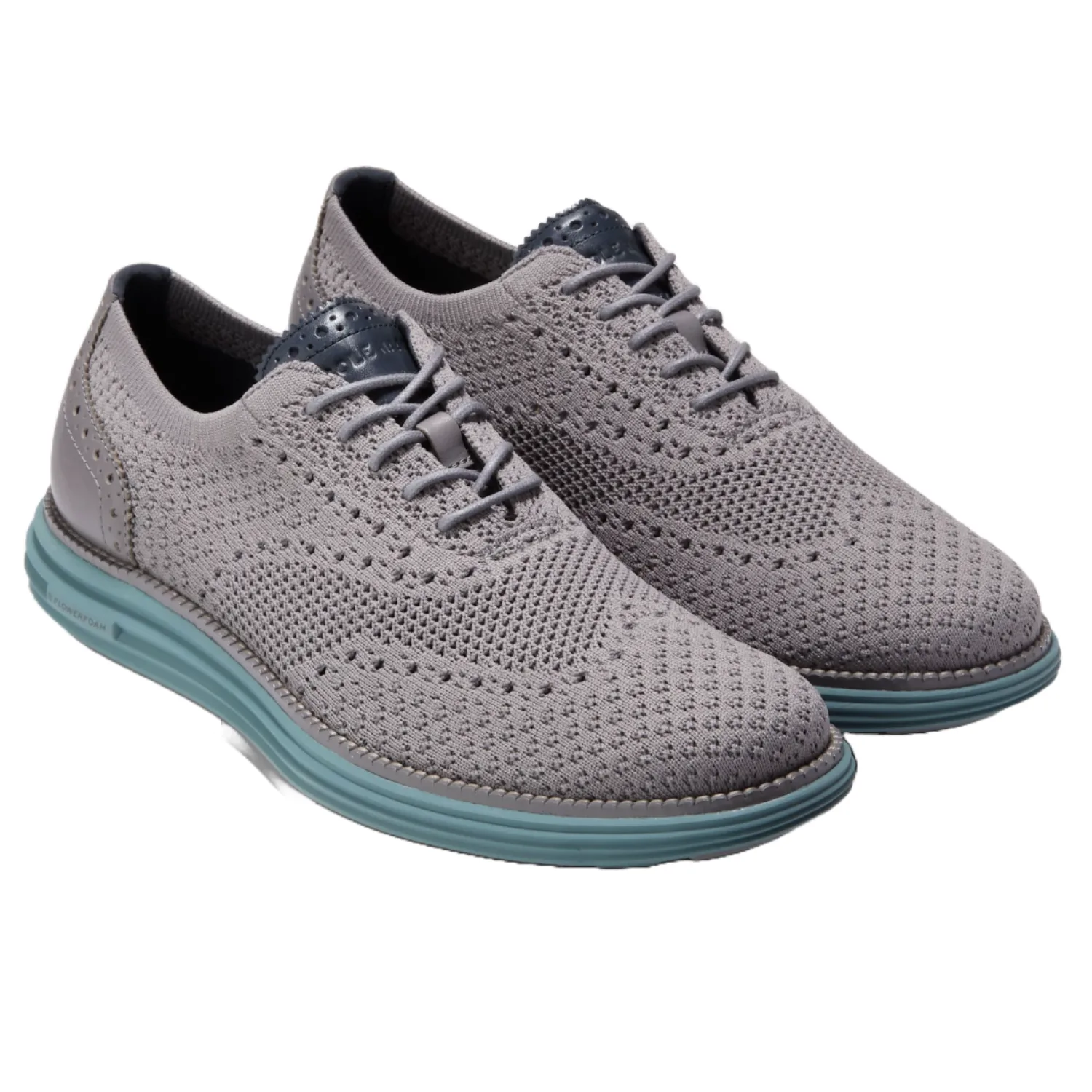 Cole Haan OriginalGrand Oxfords feature a gray knit upper with brogue detailing and a contrasting blue sole. They offer a modern, lightweight design with classic elements and are lace-up style shoes.