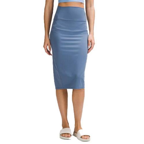 A person is wearing a blue high-waisted, knee-length pencil skirt paired with a crop top and white slide sandals.