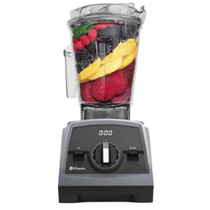 Vitamix blender filled with colorful fruits and vegetables, featuring a digital timer and adjustable speed dial on the front panel.