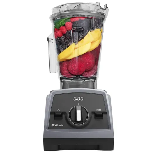 Vitamix blender filled with colorful fruits and vegetables, featuring a digital timer and adjustable speed dial on the front panel.