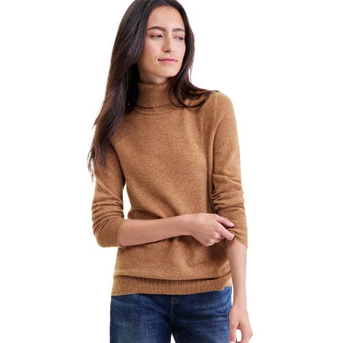 A woman is wearing a brown turtleneck sweater paired with blue jeans.