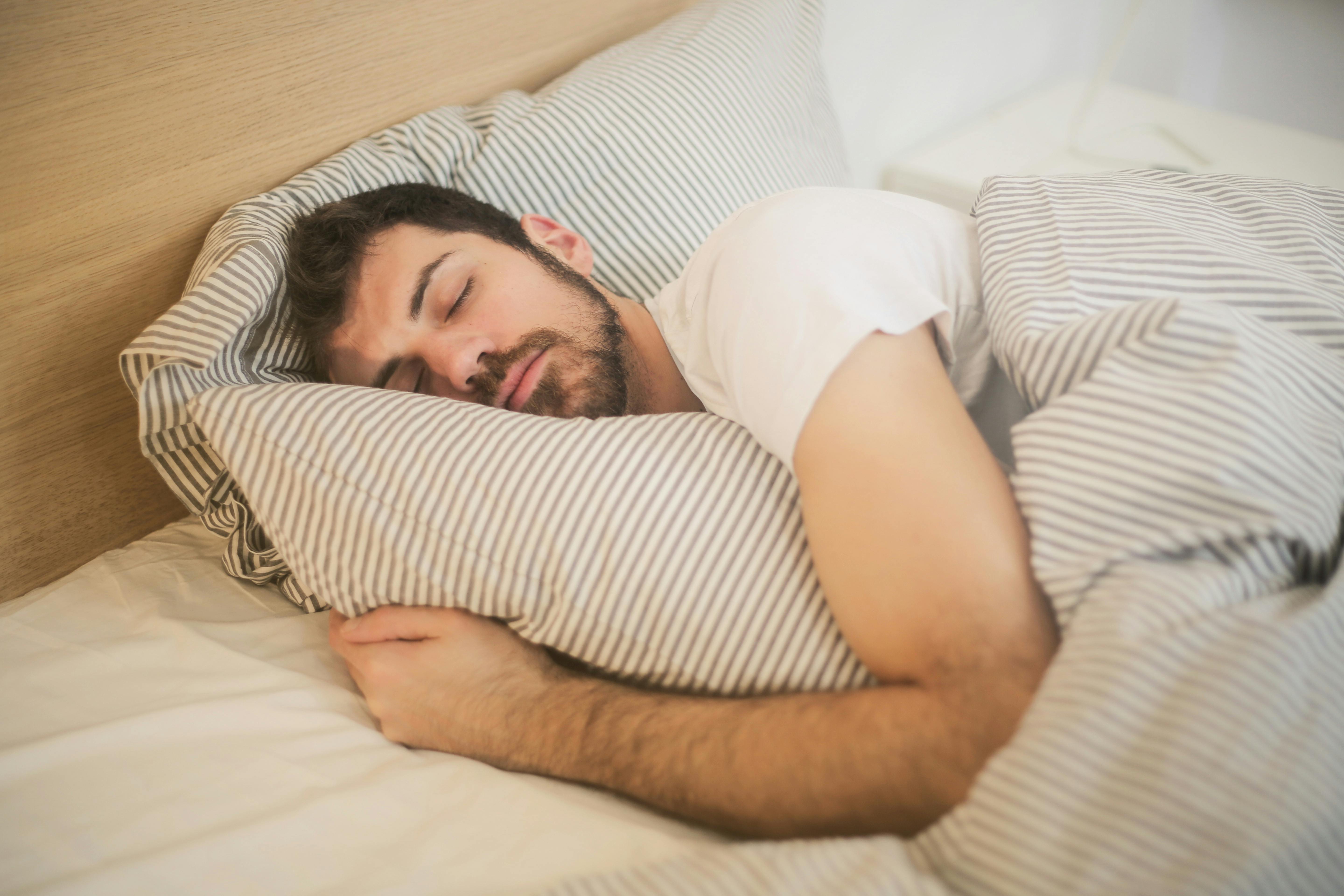 A man sleeping comfortably with striped pillows and bedding.