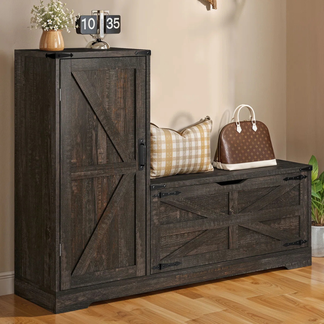 Rustic dark wooden storage bench with a single door cabinet and drawer, featuring metal hinges and handles. Topped with a small plant, a flip clock, a plaid cushion, and a brown handbag.