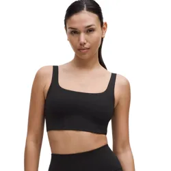 A woman is wearing a black sports bra and high-waisted black biker shorts.