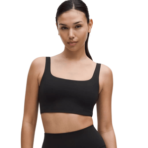 A woman is wearing a black sports bra and high-waisted black biker shorts.