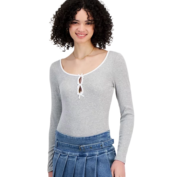 A woman is wearing a gray long-sleeve top with a scoop neckline and front cut-out detail, paired with a blue pleated skirt.