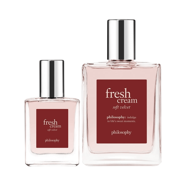 Two bottles of \“Fresh Cream Soft Velvet\“ by Philosophy, featuring smaller and larger sizes with silver caps and a red label.