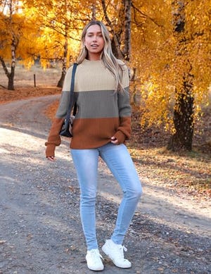 A women's turtleneck sweater with horizontal stripes in olive green, light tan, and brown, featuring a loose fit and long sleeves.