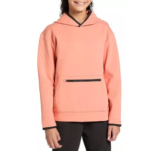 A person wearing a peach-colored hoodie with black trim and a zippered front pocket, paired with black pants.