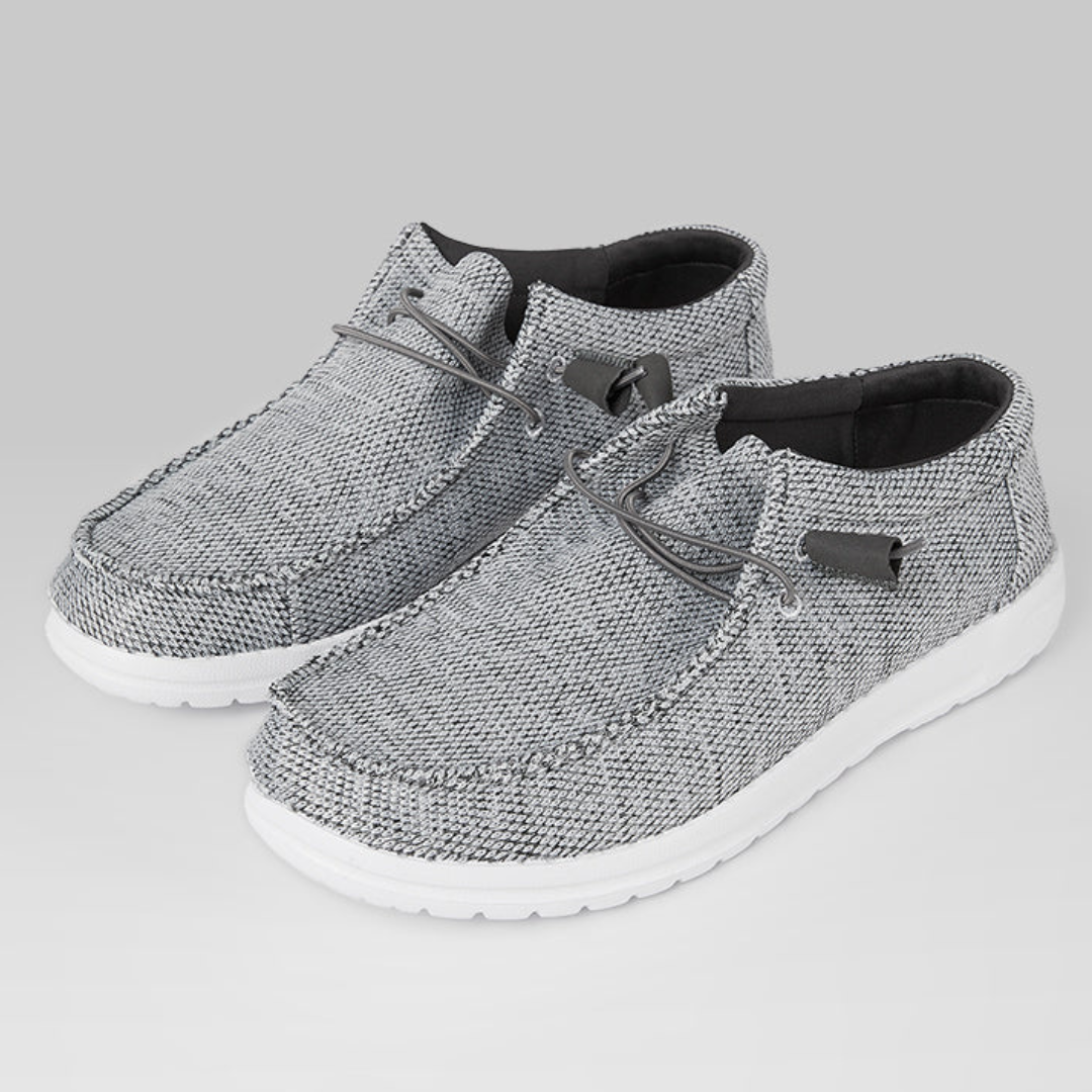 A pair of grey textile shoes with laces and white soles.