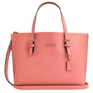 A pink Coach handbag featuring dual top handles, a detachable shoulder strap, and gold-tone hardware. The bag has a pebbled leather texture and includes a logo and hanging tag.