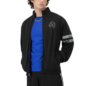 A male model wears a black Champion track jacket with a gray stripe on the sleeve and a logo on the chest, paired with a blue shirt.