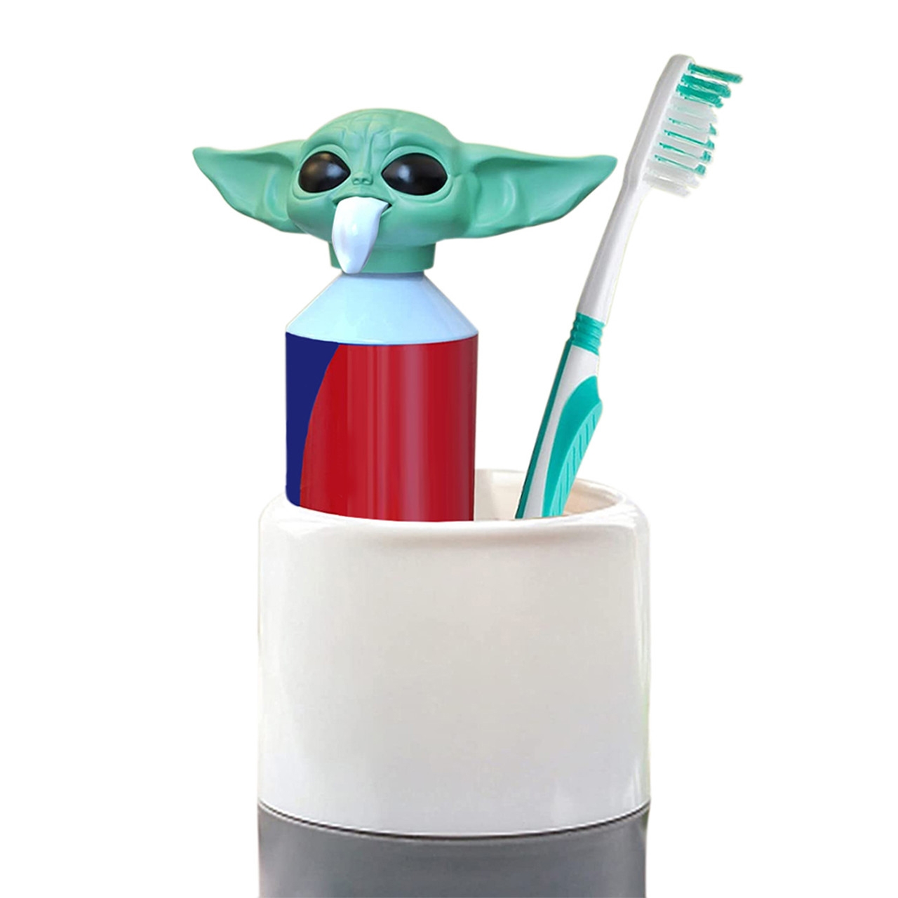 A toothpaste dispenser shaped like Baby Yoda's head dispenses toothpaste through its mouth, sitting in a holder alongside a teal and white toothbrush.