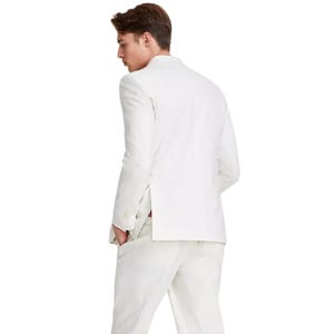 A man is wearing a white suit viewed from the back, showcasing the jacket and pants with a clean, tailored look. The suit features a single-vent back and side pockets.