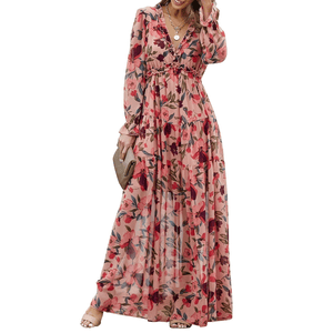 Floral Ruffled Maxi Dress with a pink base and vibrant floral print, featuring a deep V-neckline, long sleeves, ruffled details, and a tiered skirt. Paired with a beige clutch and nude open-toe sandals.