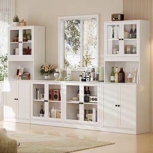 A white kitchen pantry with multiple glass-front cabinets and bookcases, featuring storage for books, bottles, kitchen appliances, and decorative items, with a modern design and sleek handles.