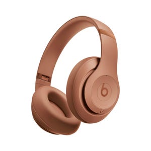Copper-colored Beats Studio Pro over-ear headphones with cushioned ear pads and a sleek design featuring the iconic \“b\“ logo on the ear cups.