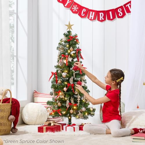 A 4-foot pre-lit Christmas tree is adorned with red and gold ornaments, a gold star topper, and surrounded by gifts. A girl is decorating the tree.
