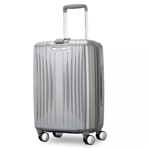 Silver hard-shell suitcase with textured vertical ridges, four spinner wheels, and a telescopic handle.