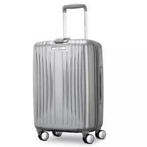Silver hard-shell suitcase with textured vertical ridges, four spinner wheels, and a telescopic handle.