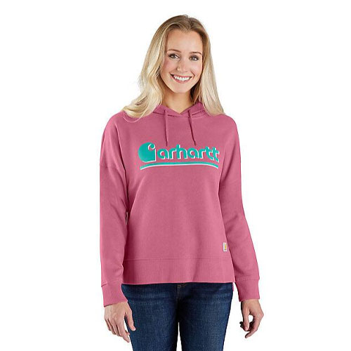 A woman wears a pink Carhartt hoodie with the brand's logo in turquoise, paired with dark jeans.